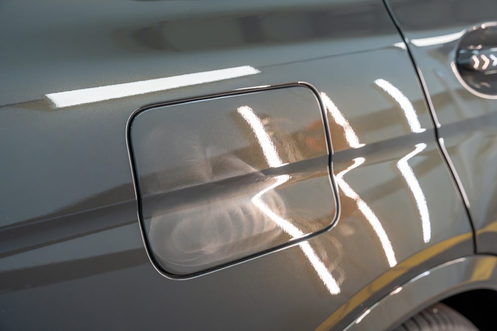 Swirl marks on a BMW fuel door seen at an angle under the shop lights