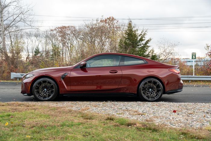 A red BMW M4 side on beside a tree line