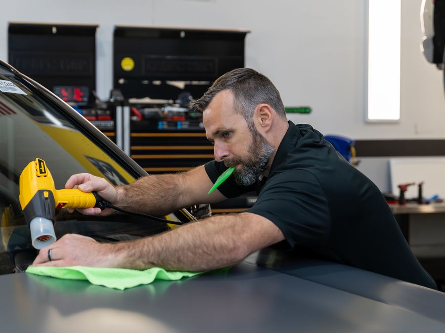 An ACP technician wiping down a panel under the ACP and XPEL signs