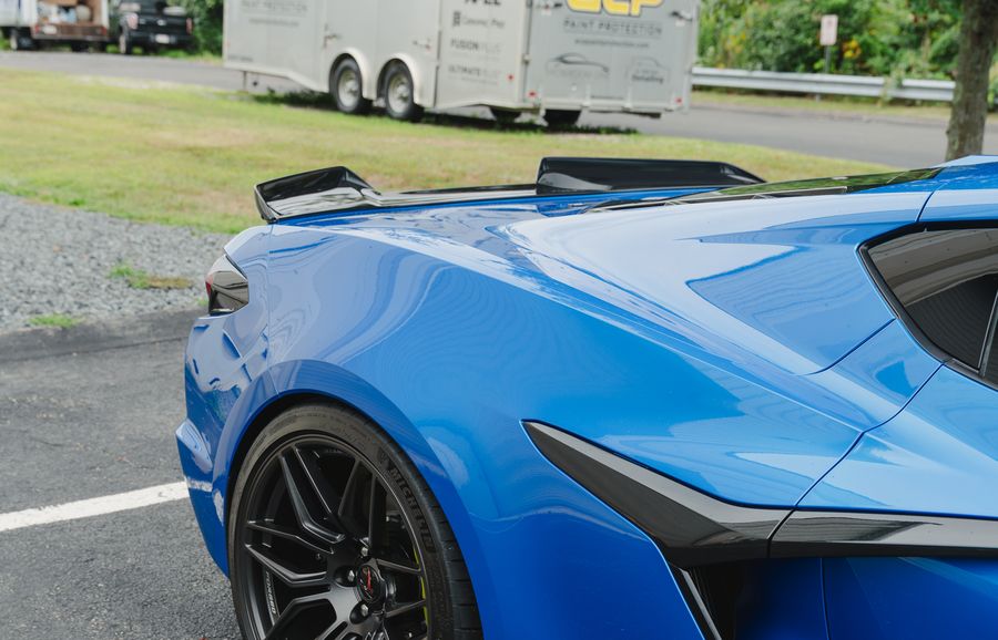 A blue Corvette from the rear three quarter, ACP's trailer behind it